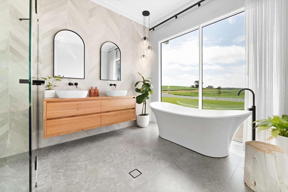 Freestanding bath and timber vanity at a picture window looking over farmland