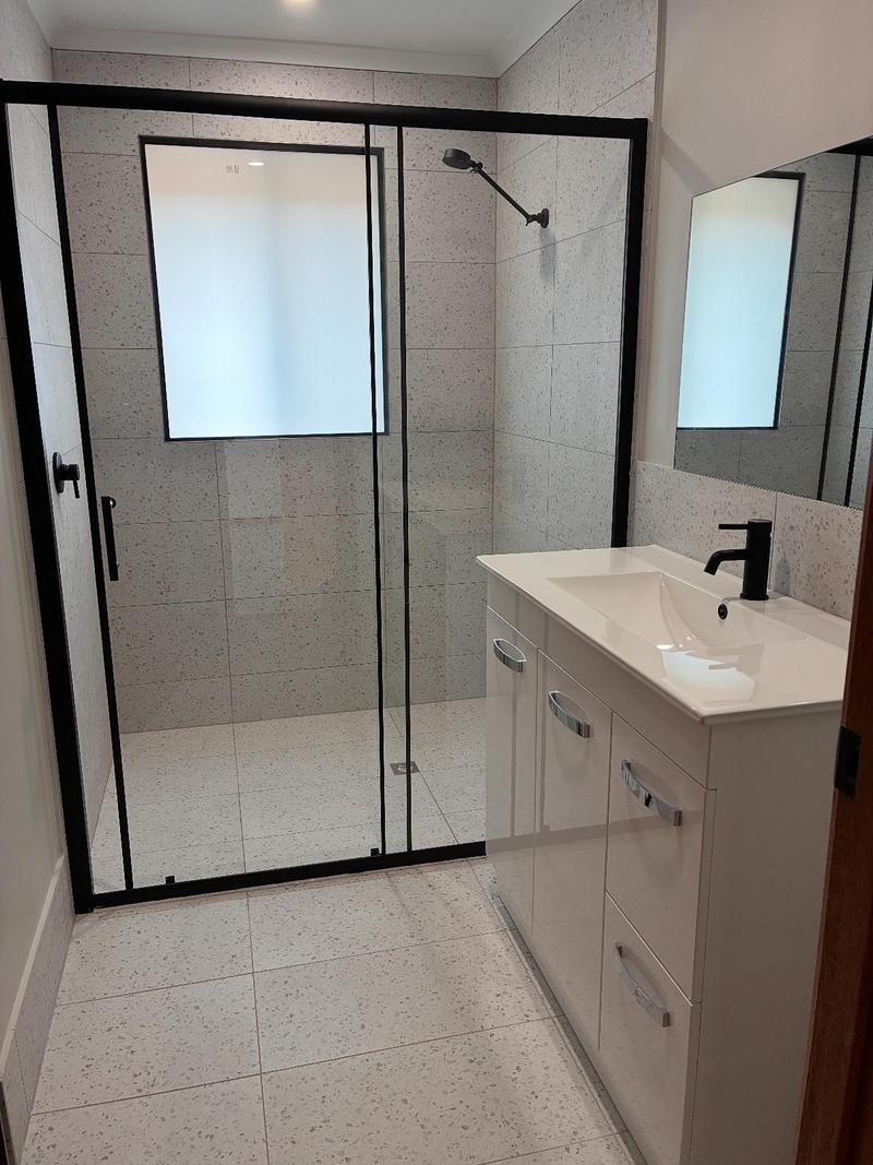 Bathroom with a black-framed sliding shower screen and white vanity