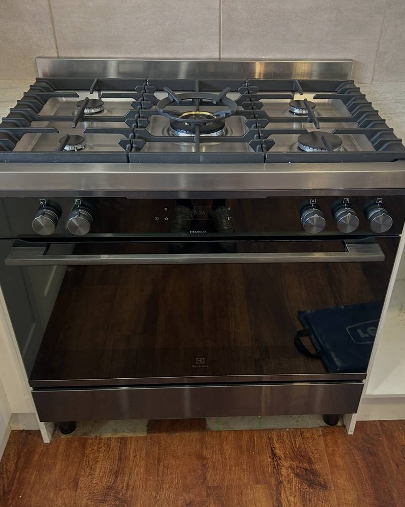 Freestanding gas cooker with a five-burner cooktop installed in a kitchen