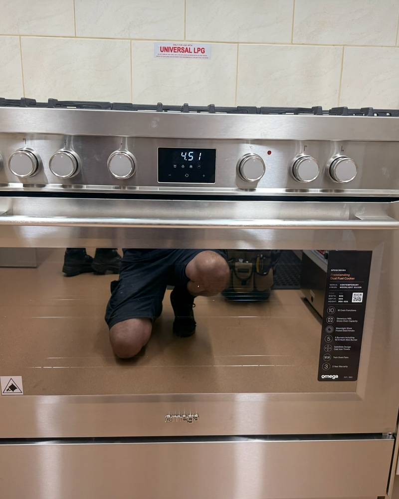 Stainless steel freestanding gas oven installed between kitchen cupboards