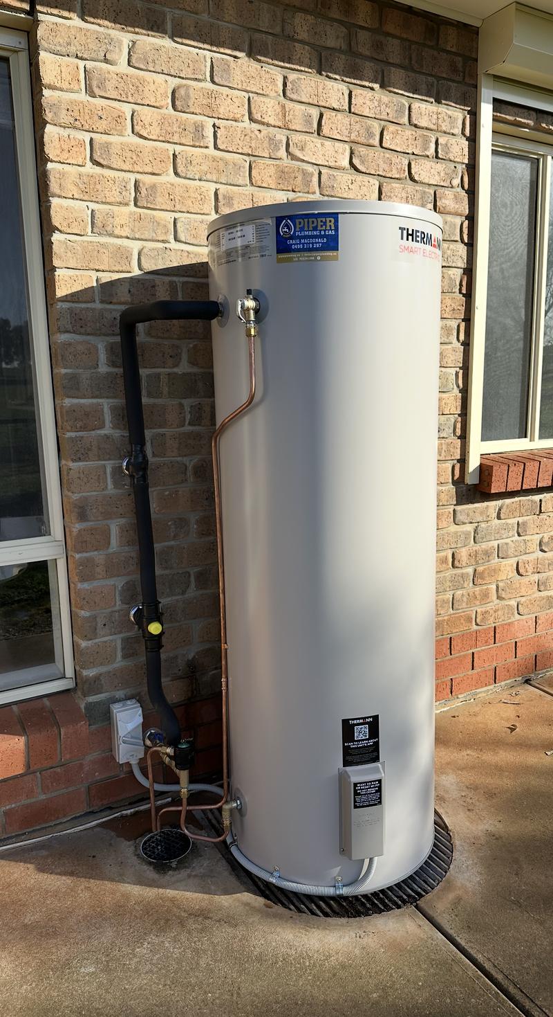 Smart electric hot water tank installed outside a brick house
