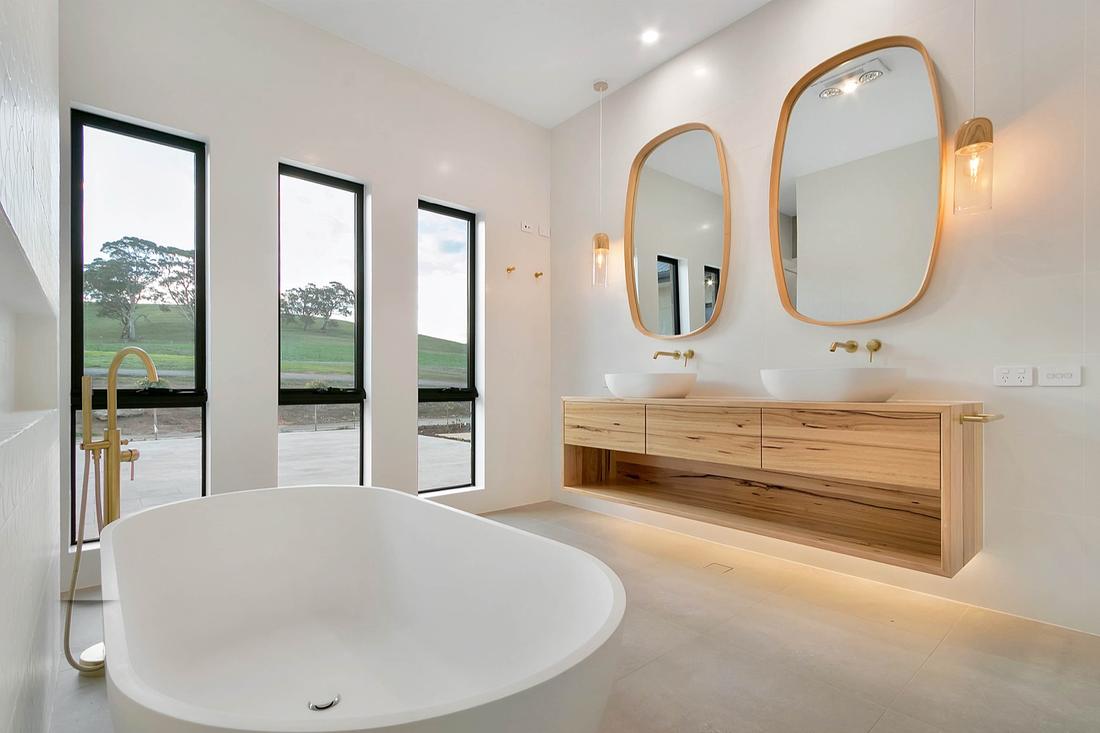 Master bathroom with oval freestanding bath, brass floor-mounted filler and twin timber mirrors