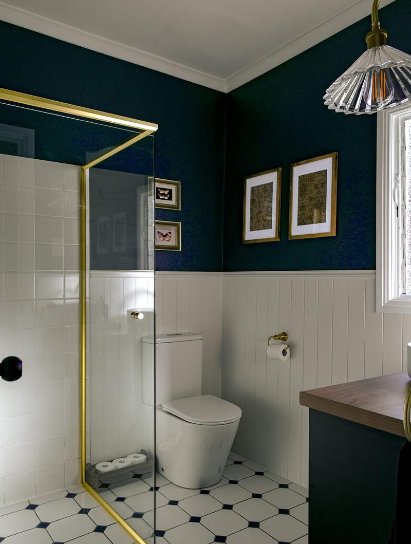 Navy and gold bathroom with a gold-framed shower screen and patterned floor tiles