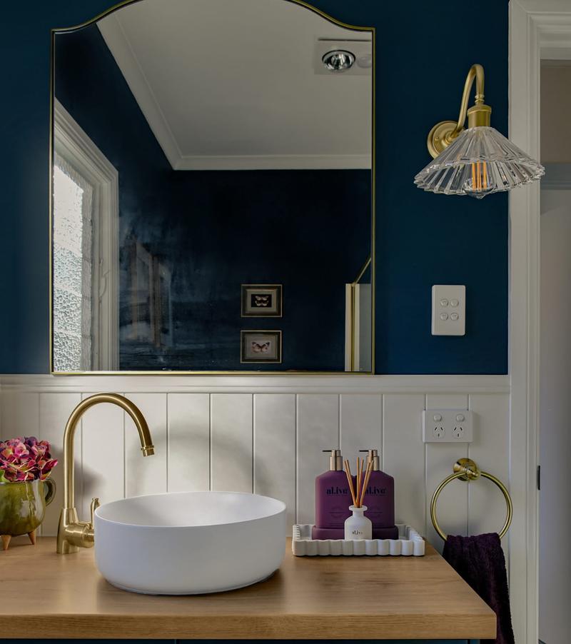 Navy vanity with a brass gooseneck tap and white basin