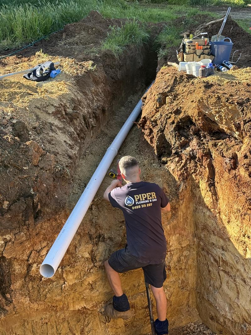Craig in a deep trench laying a new PVC sewer line