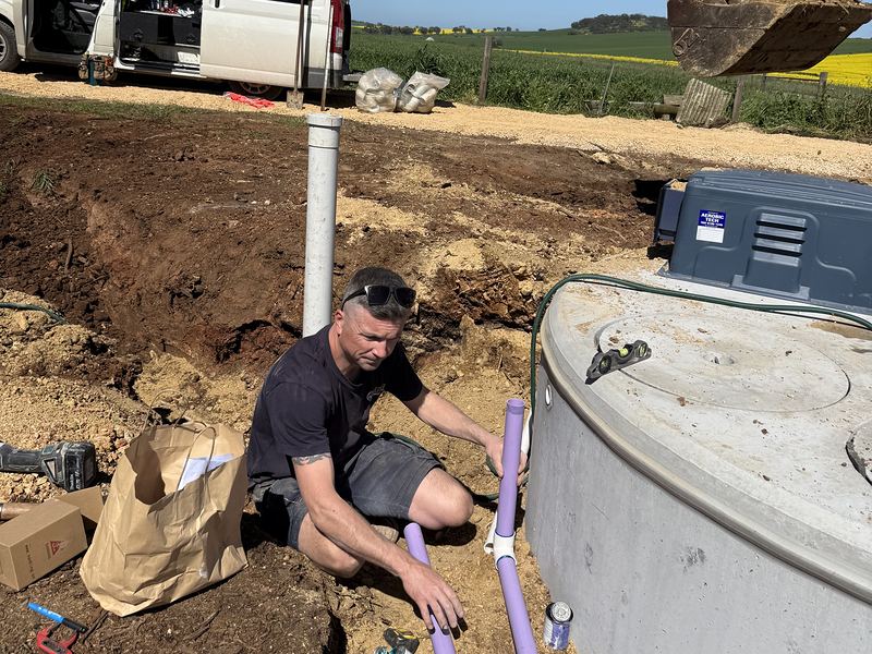 Craig connecting pipework to a new wastewater tank on a rural block