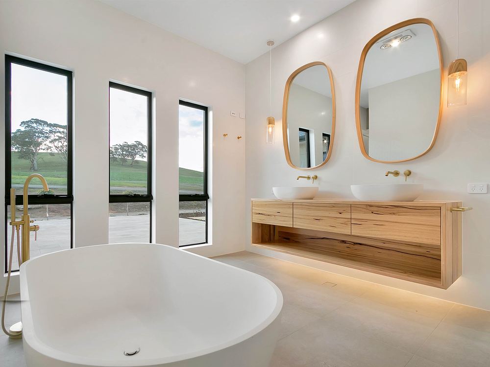 Master bathroom with an oval freestanding bath, brass tapware and twin timber mirrors
