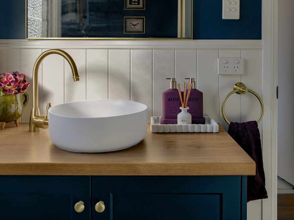 Navy vanity with a round basin and brass gooseneck tap