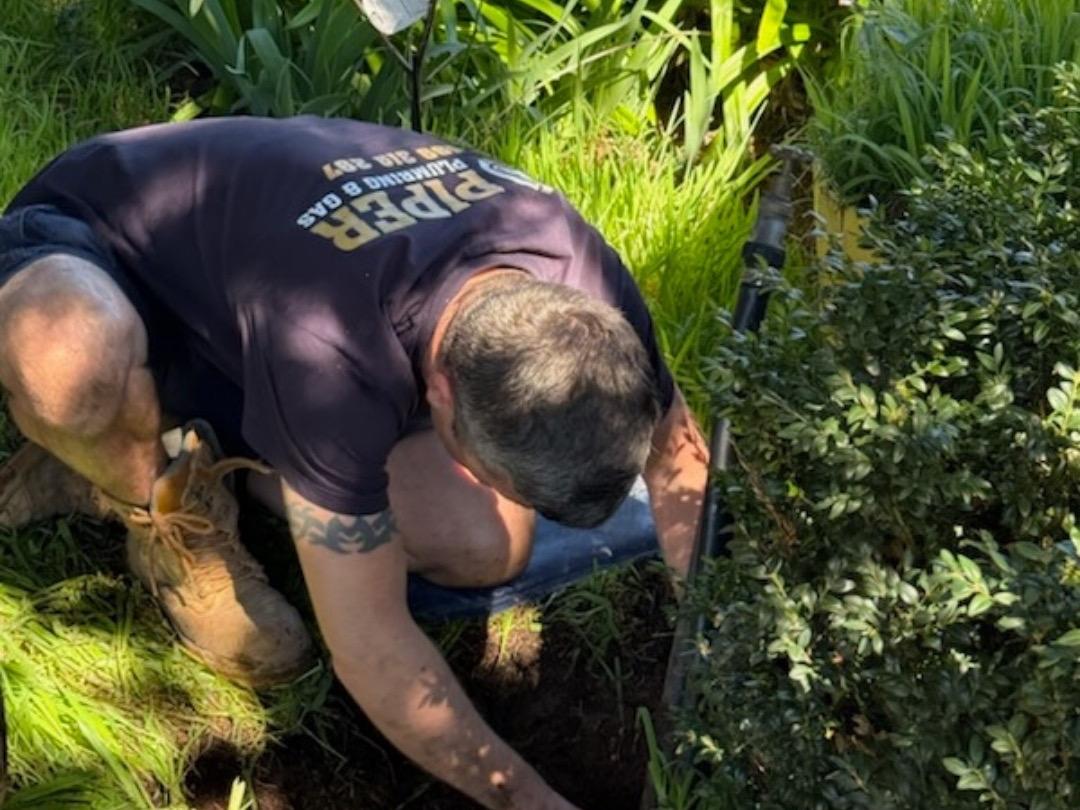 Craig digging down to a drain in a garden bed