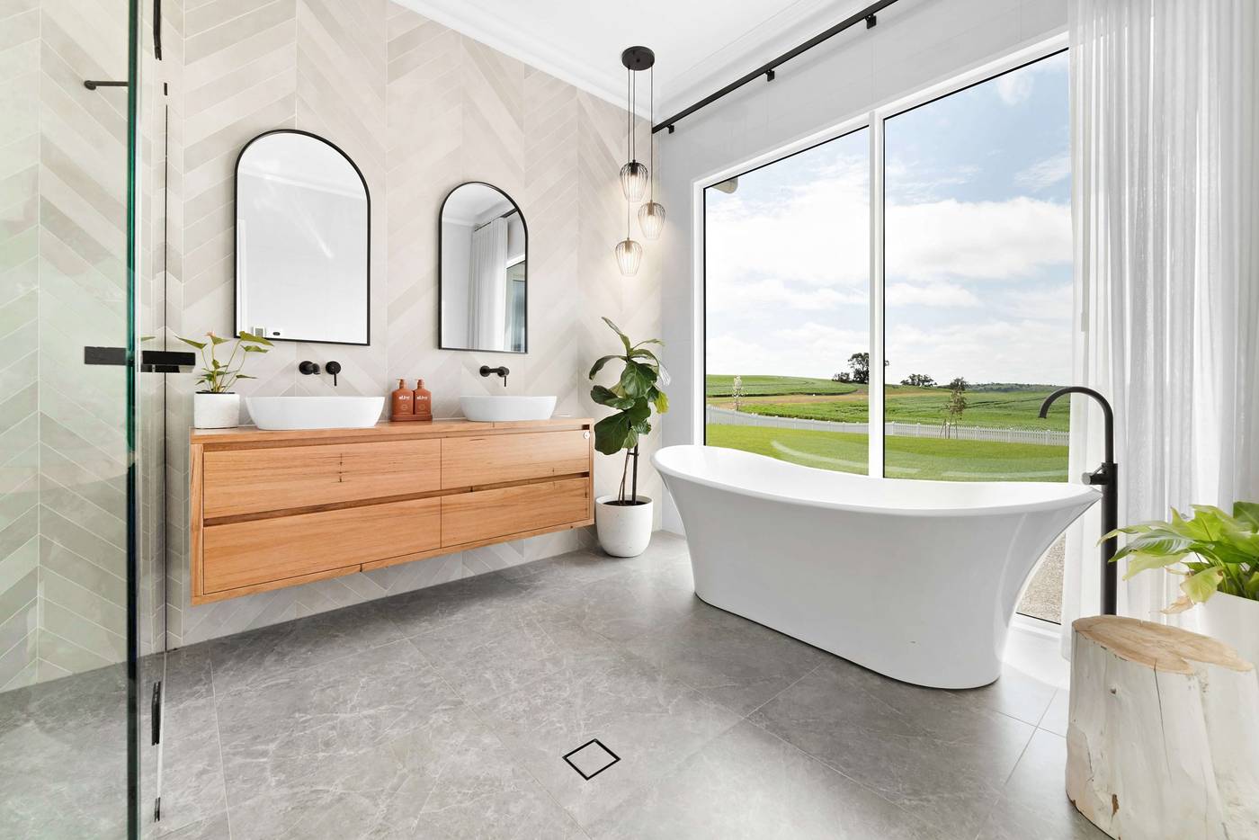 Freestanding bath beside a picture window looking out over farmland