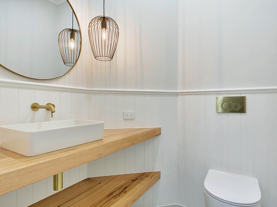 Powder room with a brass wall tap over a basin on a timber shelf