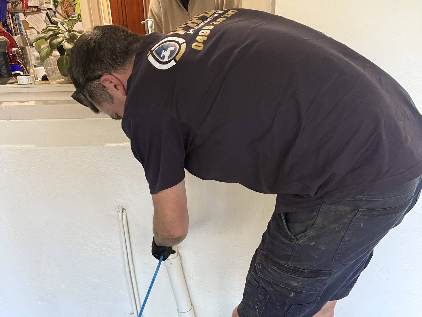 Craig clearing a blocked drain inside a house, with the drain cleaning hose beside him