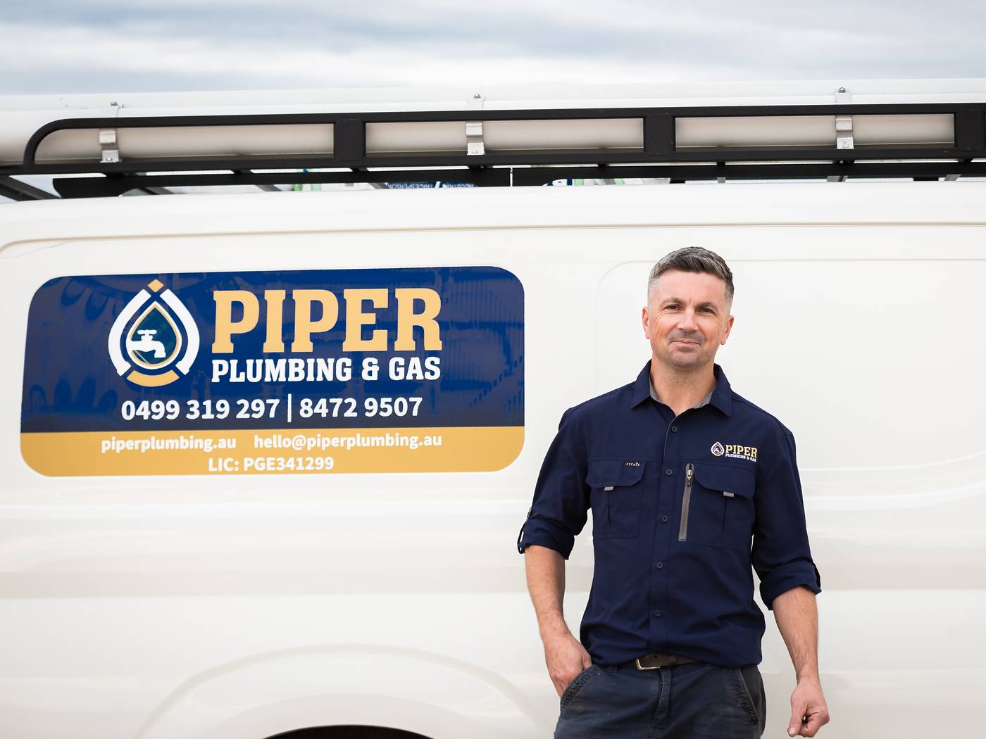 Craig beside the Piper Plumbing & Gas van, with the phone numbers and licence on the door