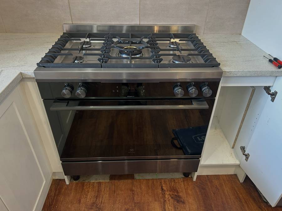 Freestanding gas cooker with a five-burner cooktop installed in a kitchen with timber floors