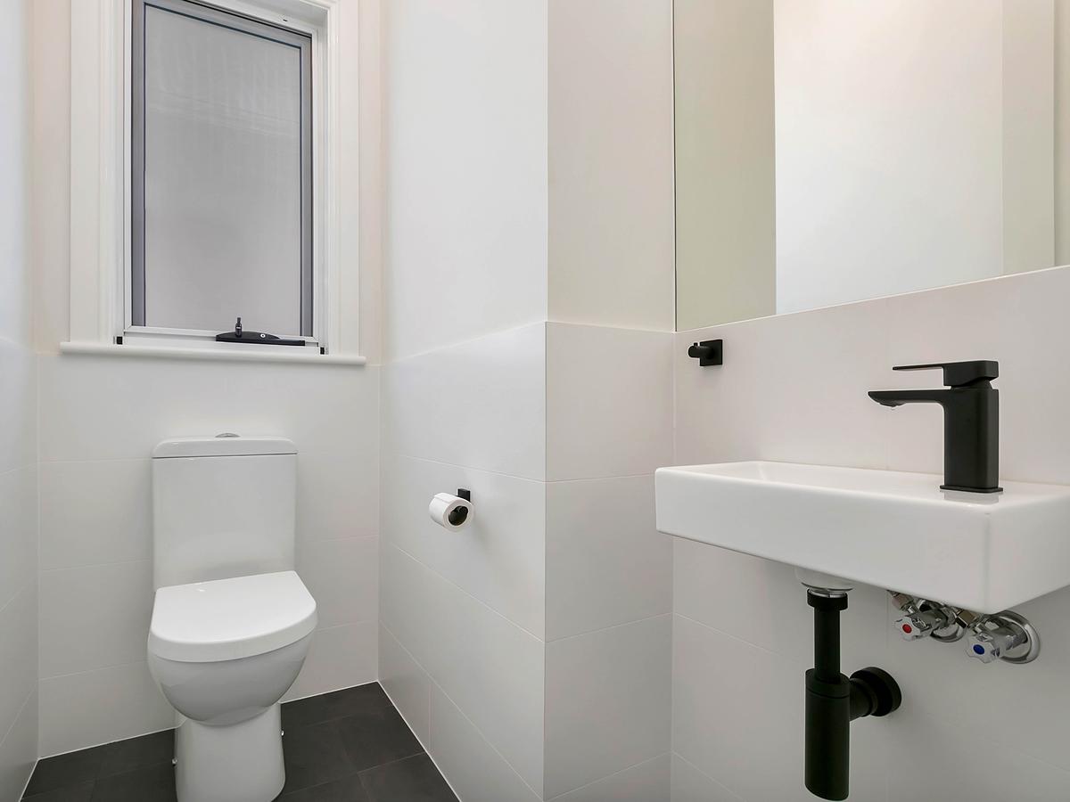 Powder room with a toilet and a wall-hung basin with black tapware