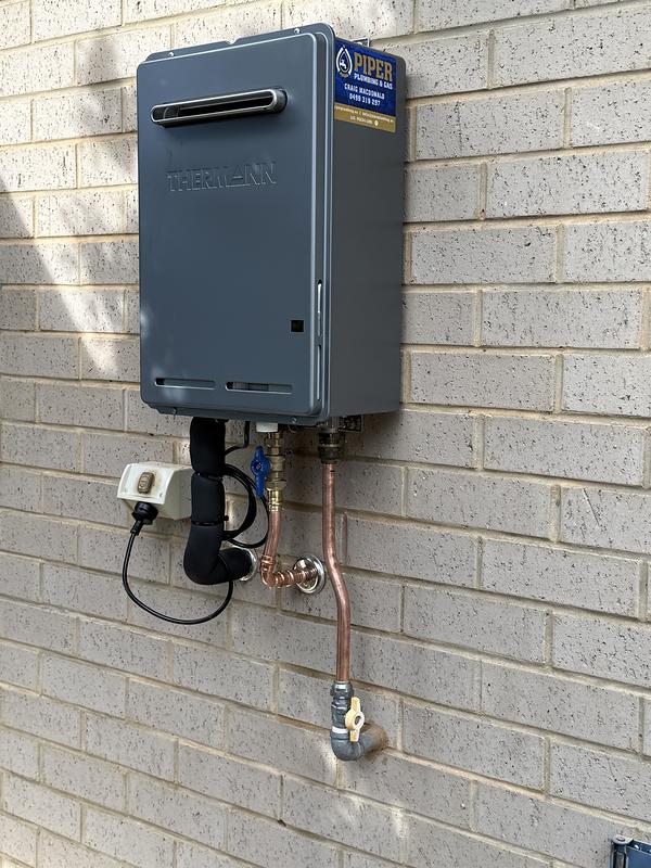 Continuous-flow gas hot water unit mounted on a brick wall