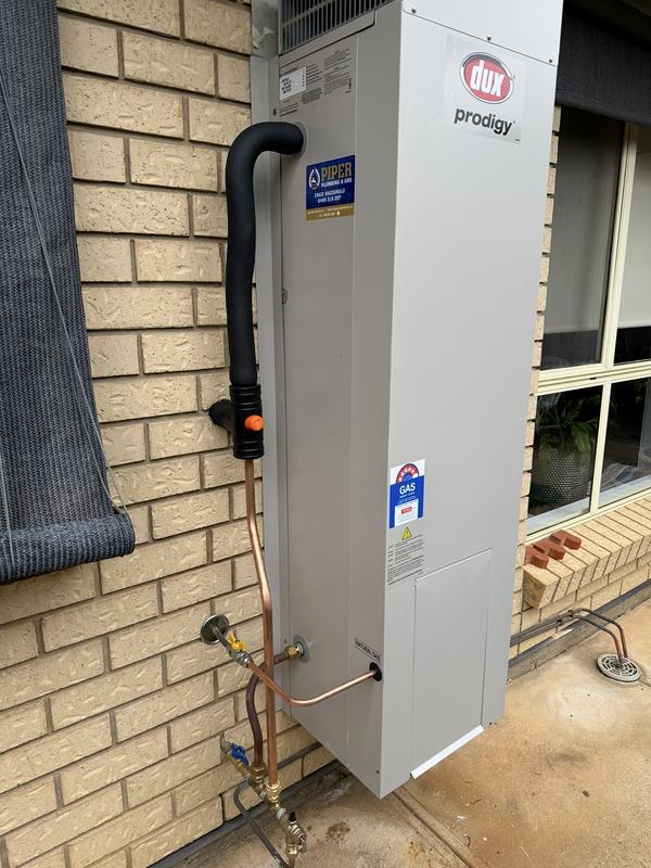 Gas storage hot water system installed against a brick wall