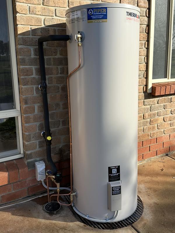 Smart electric hot water storage tank installed outside a brick house
