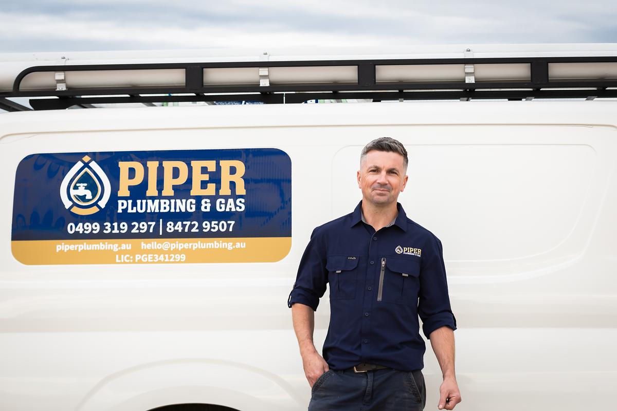 Craig beside the Piper Plumbing & Gas van, with the phone numbers and licence on the door