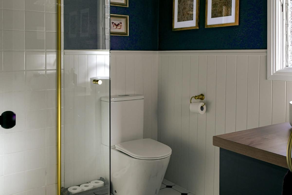 Navy and white bathroom with a toilet, brass trim and a timber vanity