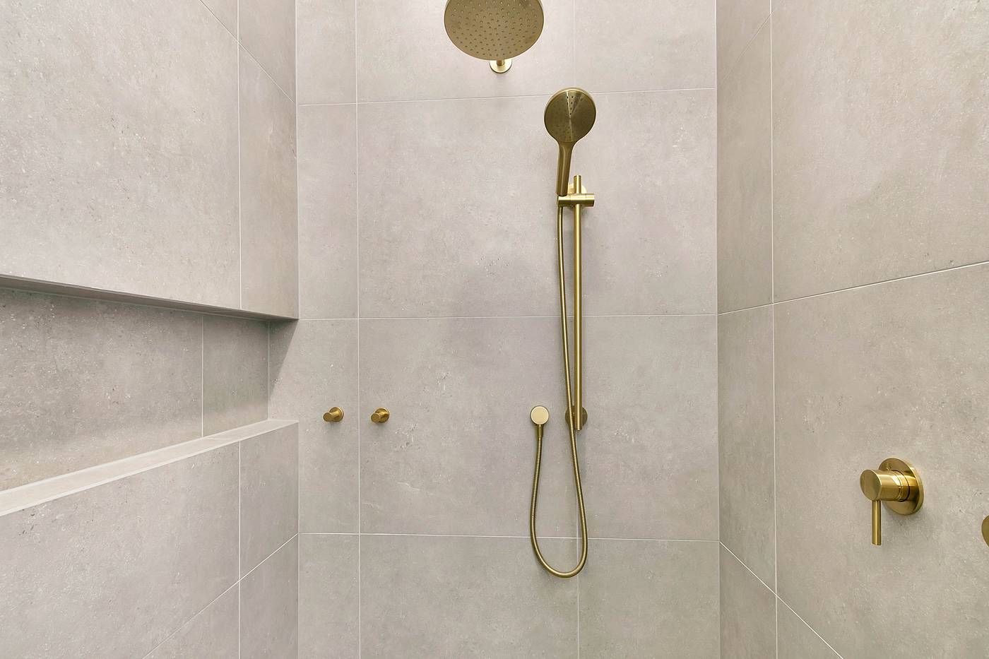 Tiled shower with a brushed brass rail shower and wall mixer