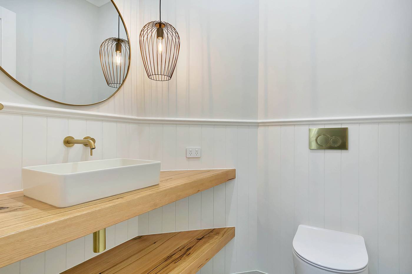Powder room with a brass wall tap over a basin on a timber shelf