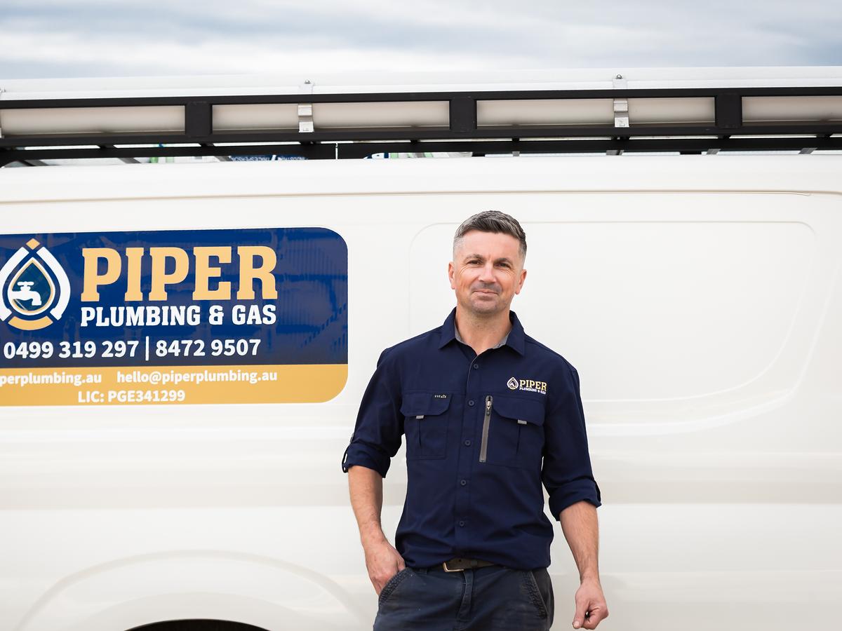 Craig beside the Piper Plumbing & Gas van, with the phone numbers and licence on the door